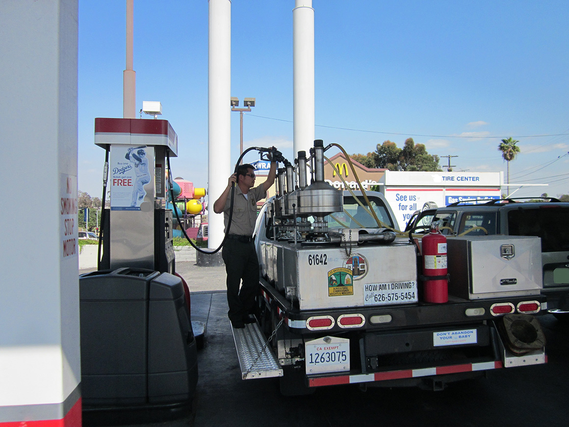 A man filling tanks on his truck up with gas.
