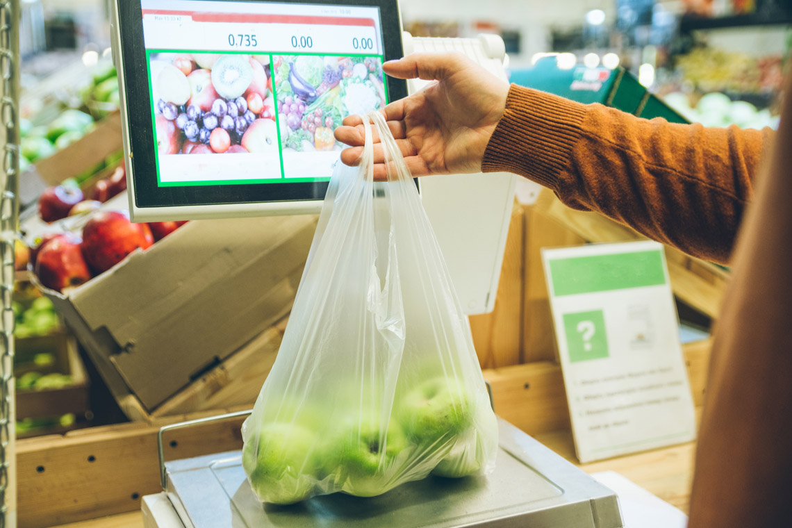 Man at grocery store weighing apples